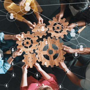 Five gears coming together overlayed by a network of people.